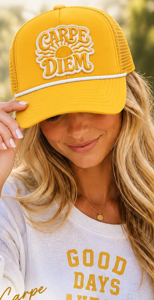 Blonde woman in a Good Days Ahead sweatshirt wearing the b.Honey Honey Lid Carpe Diem golden yellow trucker hat with cream sunrise embroidery