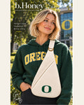 Model on the University of Oregon campus wearing the cream Honey Sling with green O mark and gold hardware