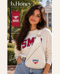 Model on the SMU campus wearing the ivory b.Honey Honey Sling with the blue SMU wordmark and red Mustang